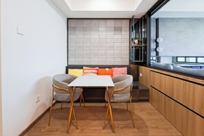 Une cuisine moderne avec un coin repas, comprenant une table blanche, deux chaises et un banc intégré agrémenté de coussins colorés.