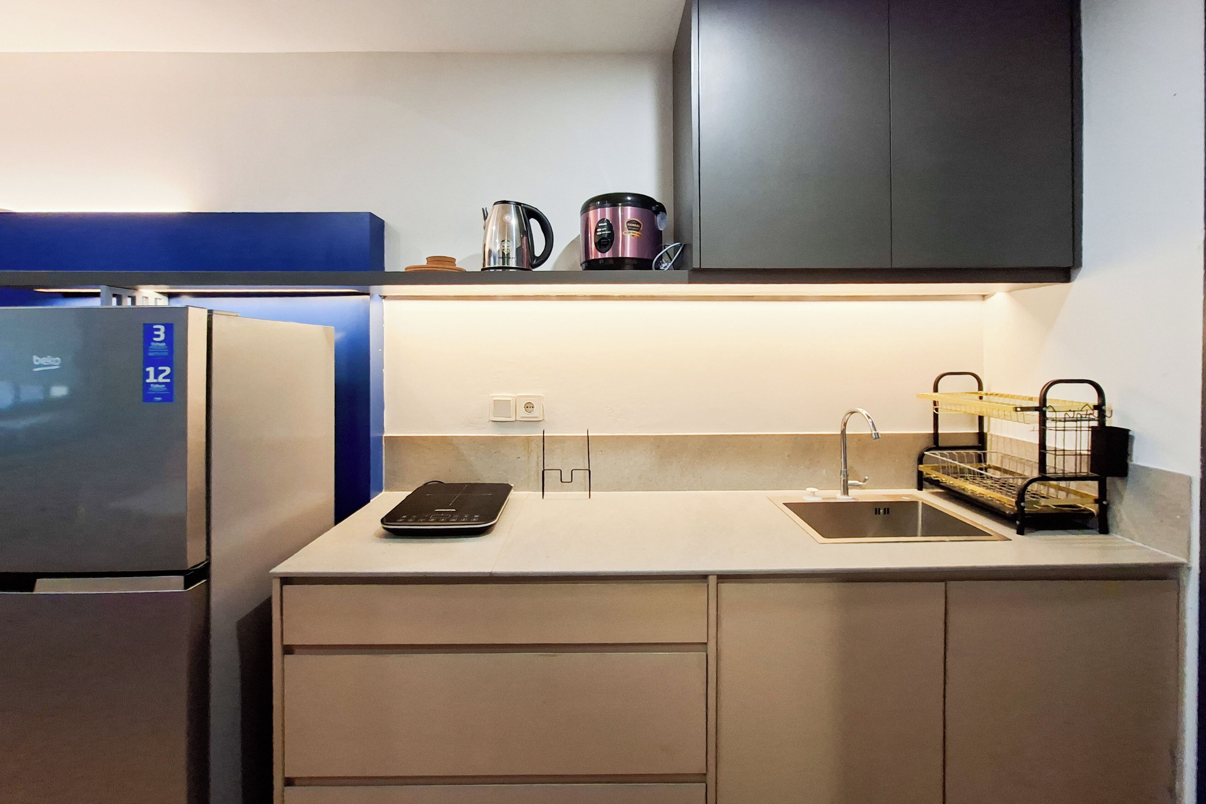 Een moderne keuken met een geïntegreerde koelkast, een koffiezetapparaat en een waterkoker op het aanrecht.