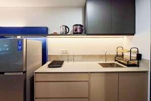 Eine moderne Küche mit integriertem Kühlschrank, einer Kaffeemaschine und einem Wasserkocher auf der Arbeitsfläche.