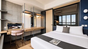 Une chambre d’hôtel moderne équipée d’un lit, d’un bureau, d’une chaise, d’un miroir et d’une fenêtre donnant sur la ville.