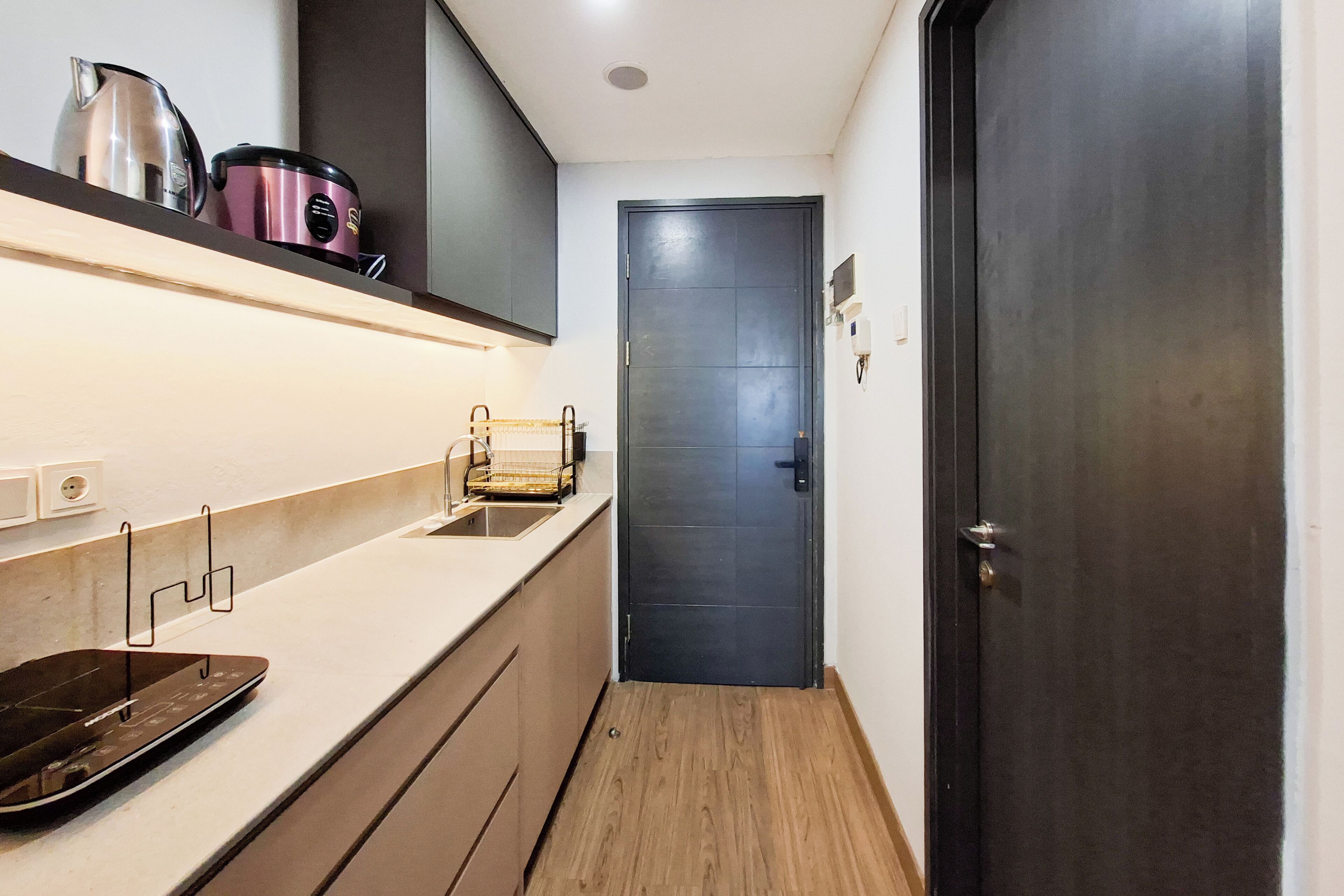 Una cocina estrecha con una encimera, un hervidor, un tostador y una puerta que da a otra habitación.