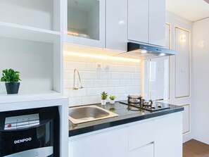Una cocina moderna con armarios blancos, un lavamanos de acero inoxidable y un horno empotrado.