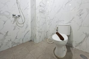 Ein Badezimmer mit Toilette, Dusche und Marmorwand.