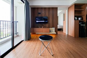 Ein Hotelzimmer mit Holzboden, einem an der Wand montierten Fernseher, einem kleinen Tisch und einem Balkon mit Blick.