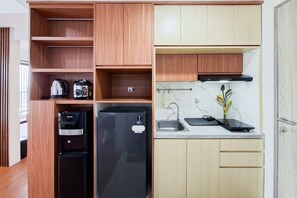 Cozinha compacta com geladeira embutida, cafeteira e chaleira.