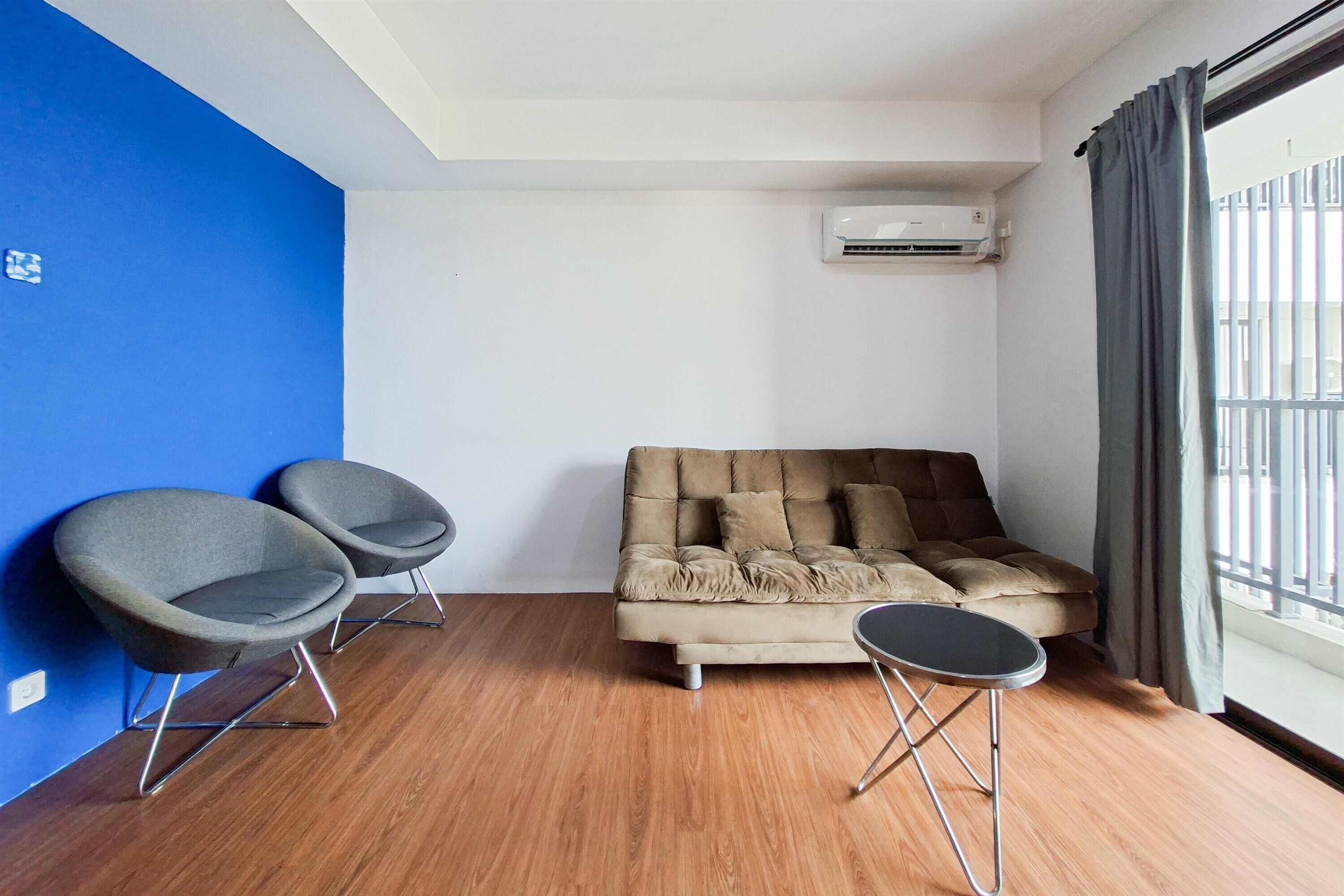 Une pièce comprenant un canapé, deux fauteuils, une petite table et un appareil de climatisation.