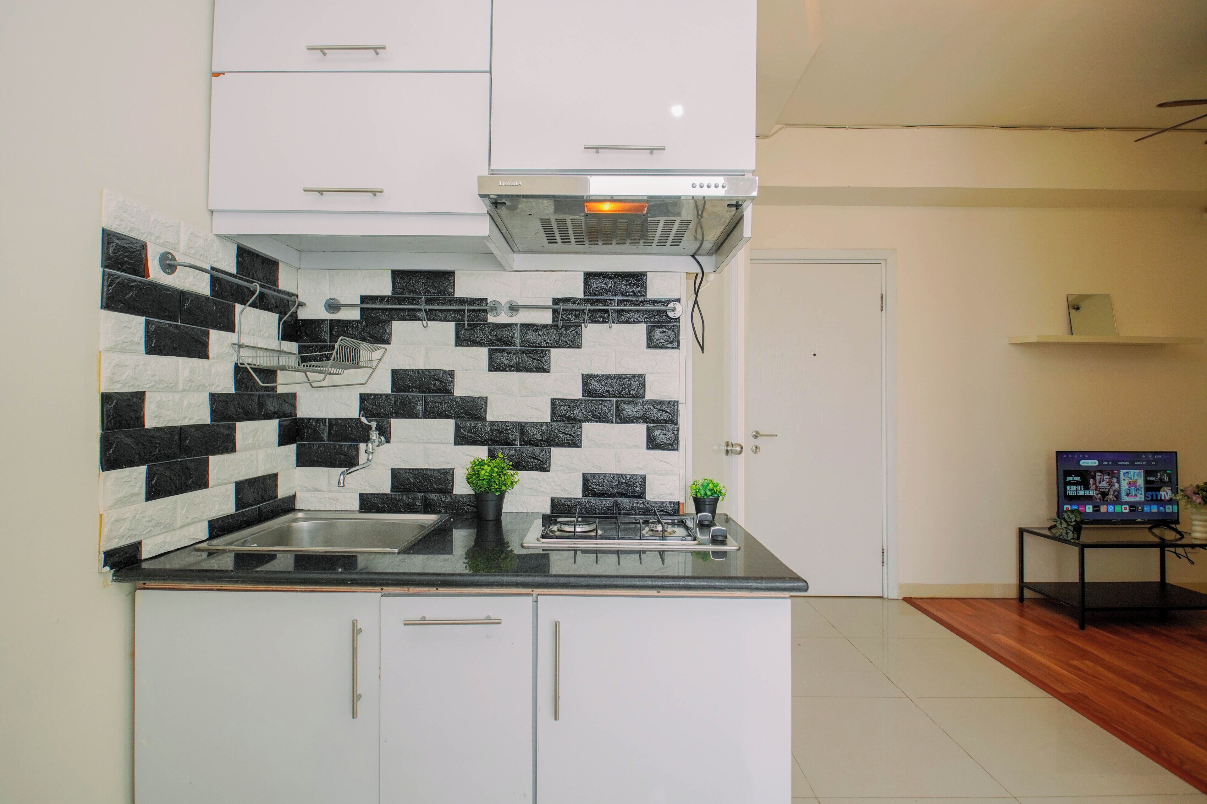 Una cocina moderna con un salpicadero de azulejos blanco y negro, un lavamanos de acero inoxidable y una estufa a gas.