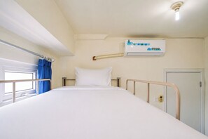 A single-bed room with a window, a wall-mounted air conditioner, and a door. - Cozy Minimalist 1Br At Apartment Green Pramuka City (Jakarta)