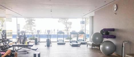 A gym with treadmills, stationary bikes, and exercise balls.