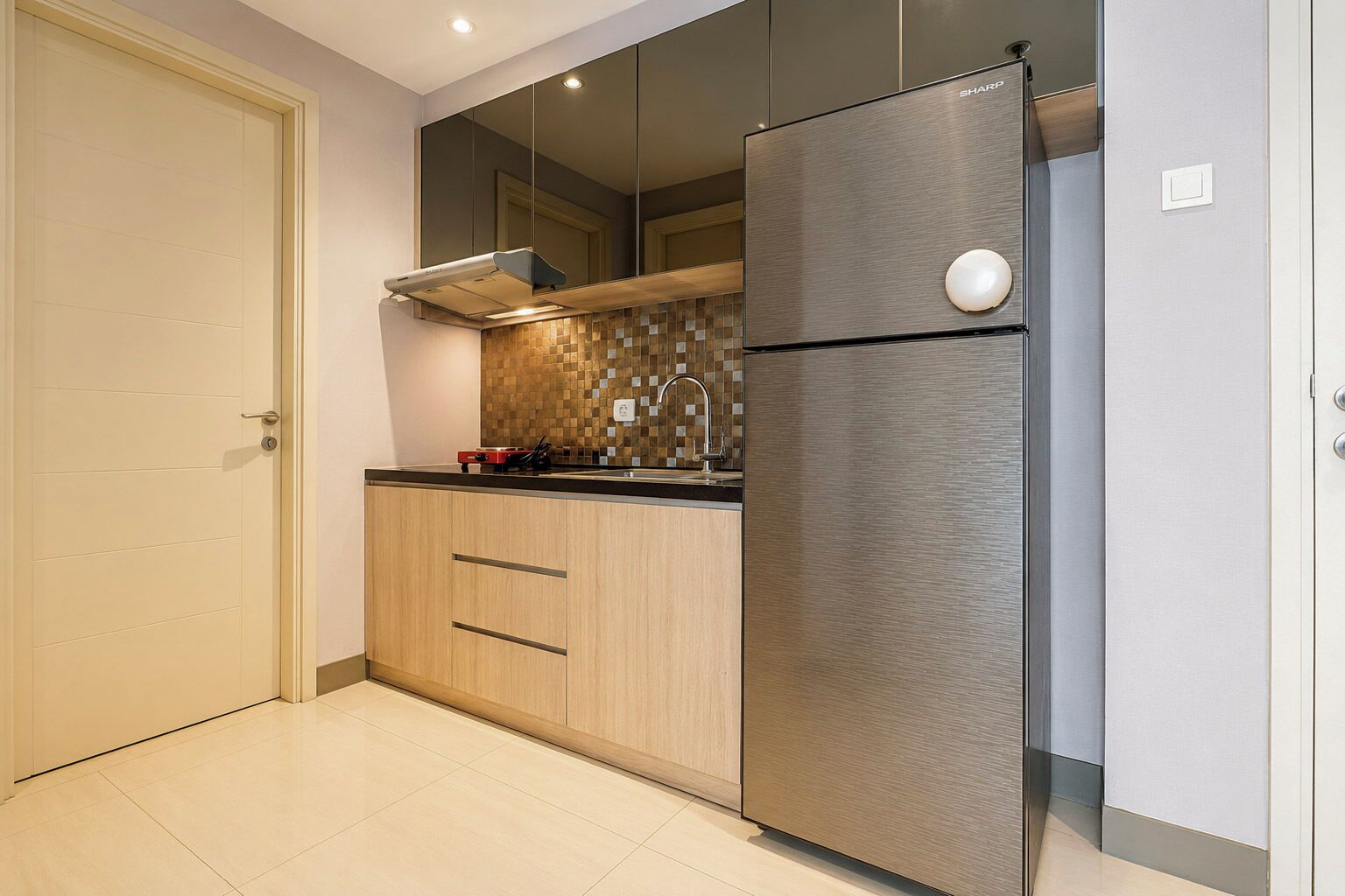 A modern kitchen with a stainless steel refrigerator, wooden cabinets, a tiled backsplash, and a recessed ceiling light.