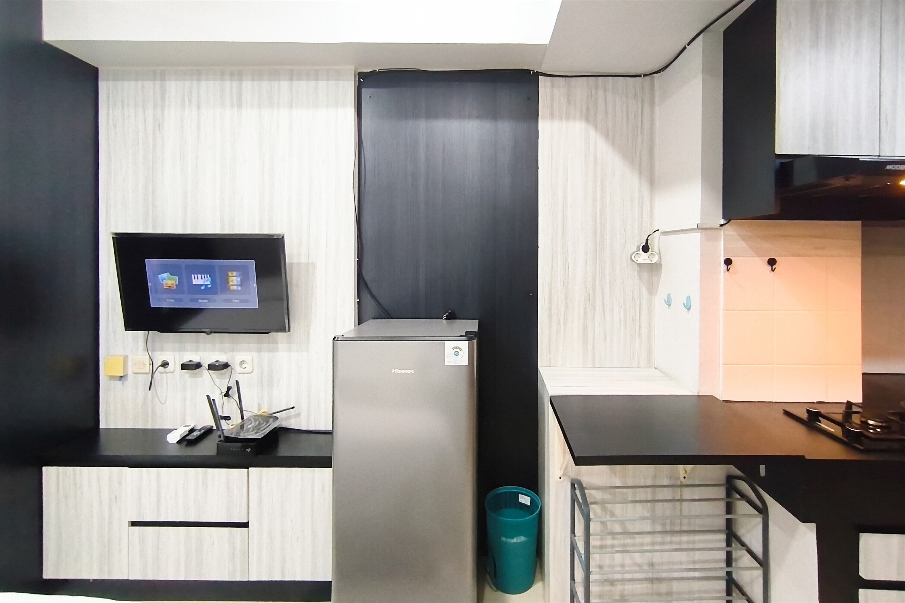 Una kitchenette compacta con televisor integrado, refrigerador y microondas.