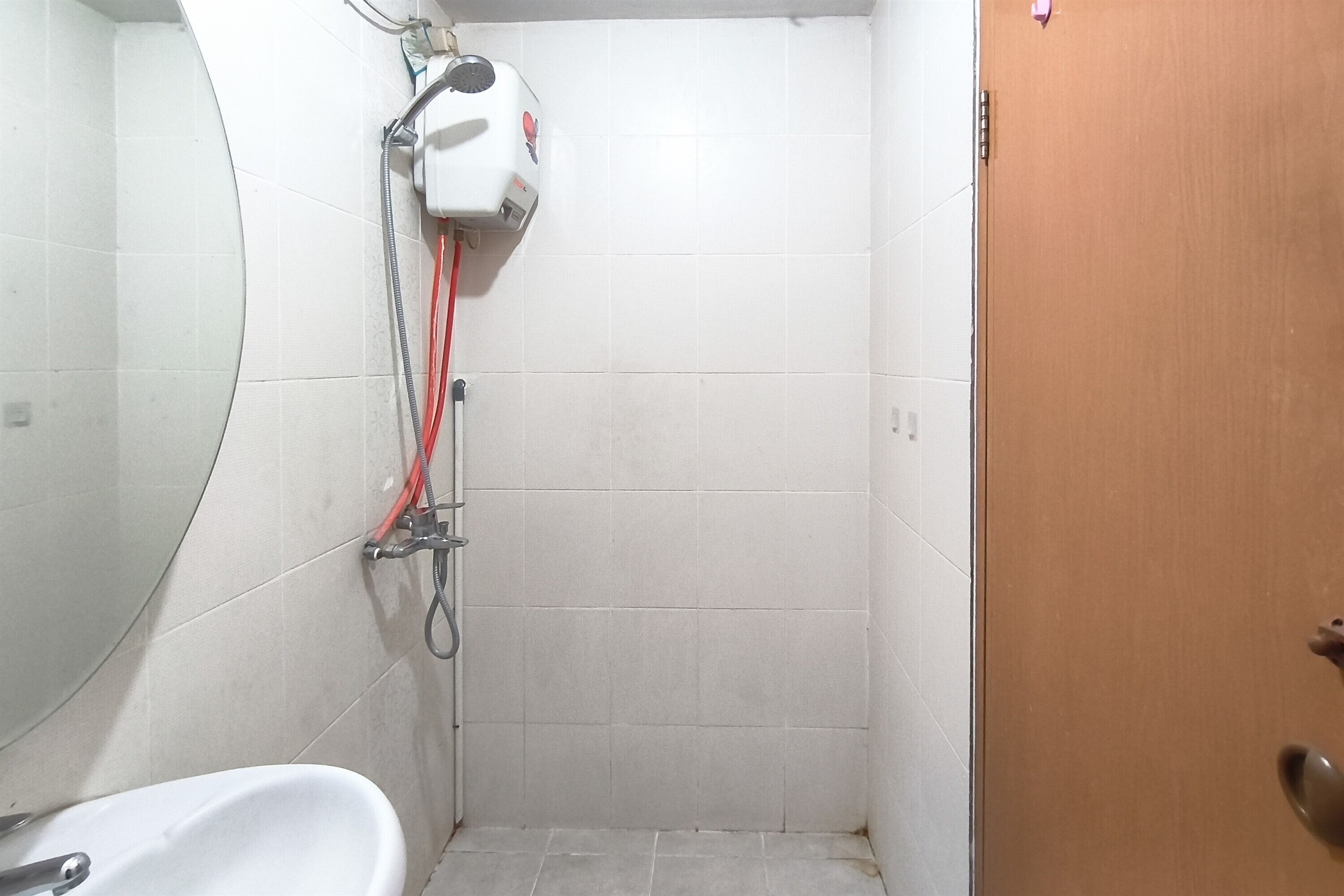 A small, tiled bathroom with a shower, a toilet, and a sink.