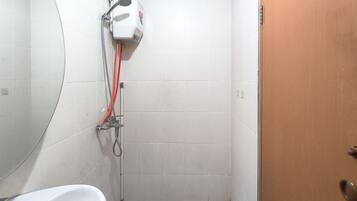 A small, tiled bathroom with a shower, a toilet, and a sink.