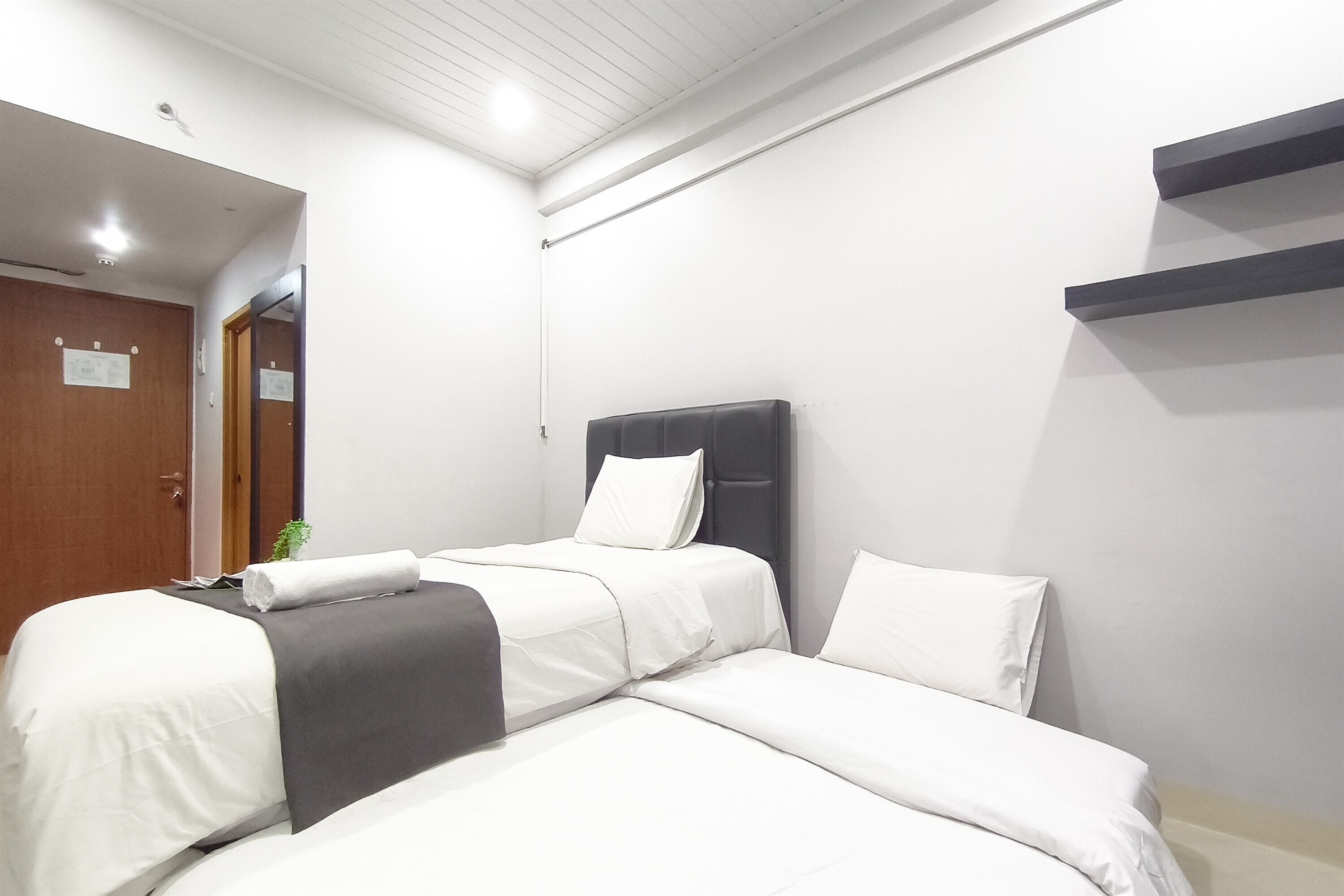 A hotel room with two beds, a wooden door, and a small plant.
