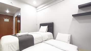 A hotel room with two beds, a wooden door, and a small plant.