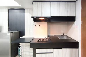 A compact kitchen with a black countertop, a stainless steel sink, and a gas stove.