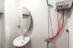 A bathroom with a white sink, a mirror, and a handheld showerhead.