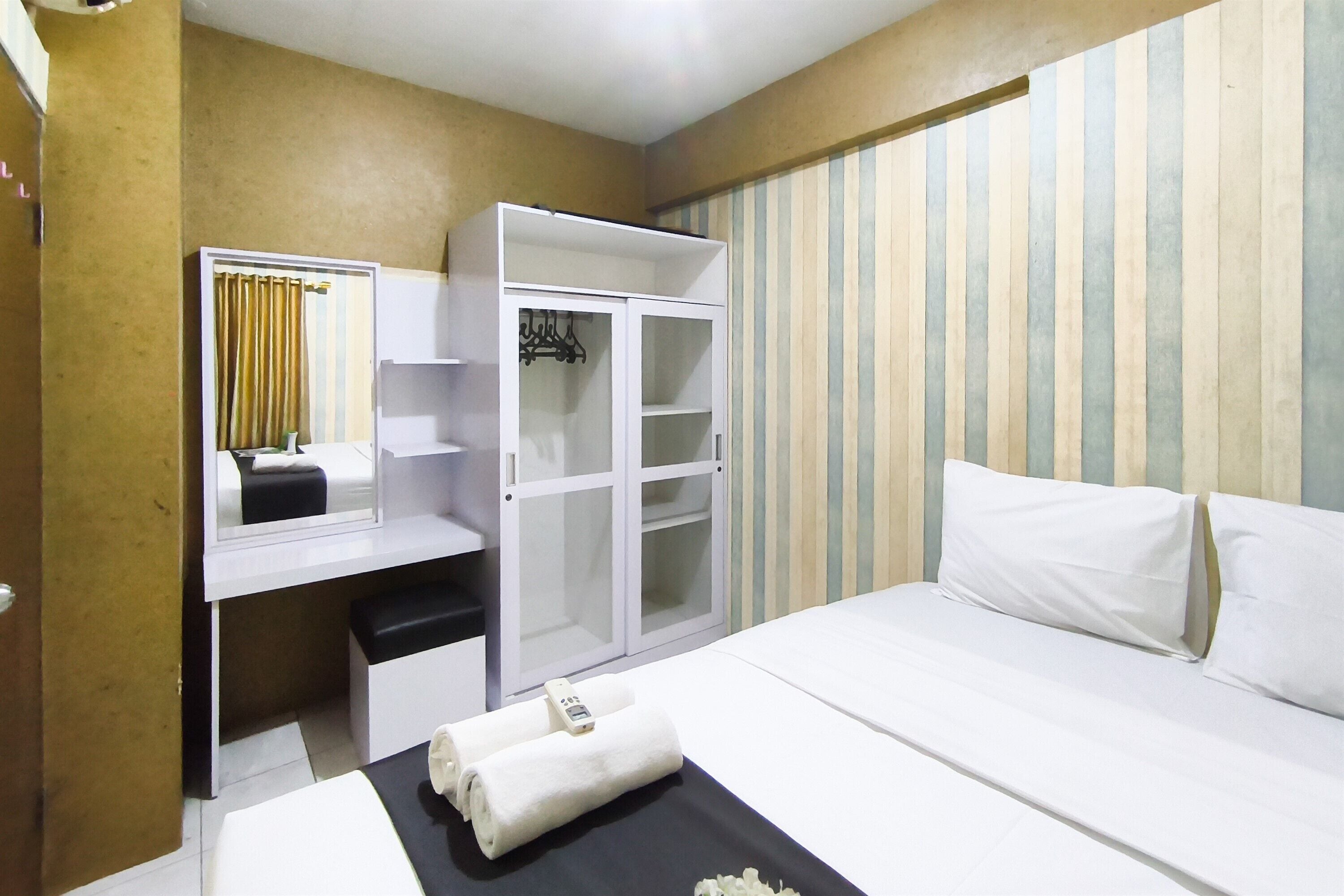 A hotel room with a bed, a desk, a wardrobe, and a striped wall.