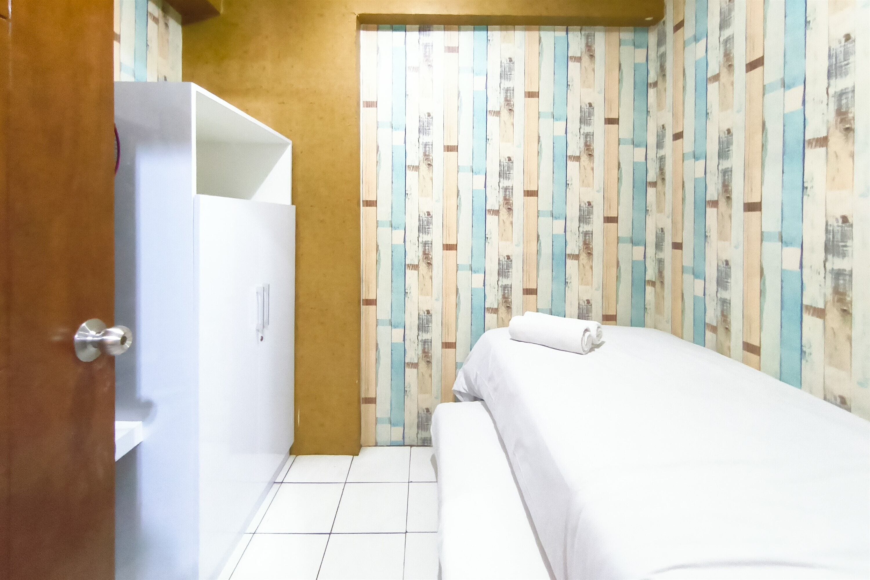 A hotel room with a bed, a wardrobe, and a door.