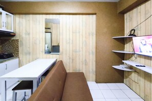Une cuisine compacte avec un mur en bois, un plan de travail blanc et un banc.