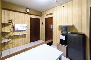 Une cuisine avec des lambris en bois, une horloge, un réfrigérateur et un distributeur d’eau.