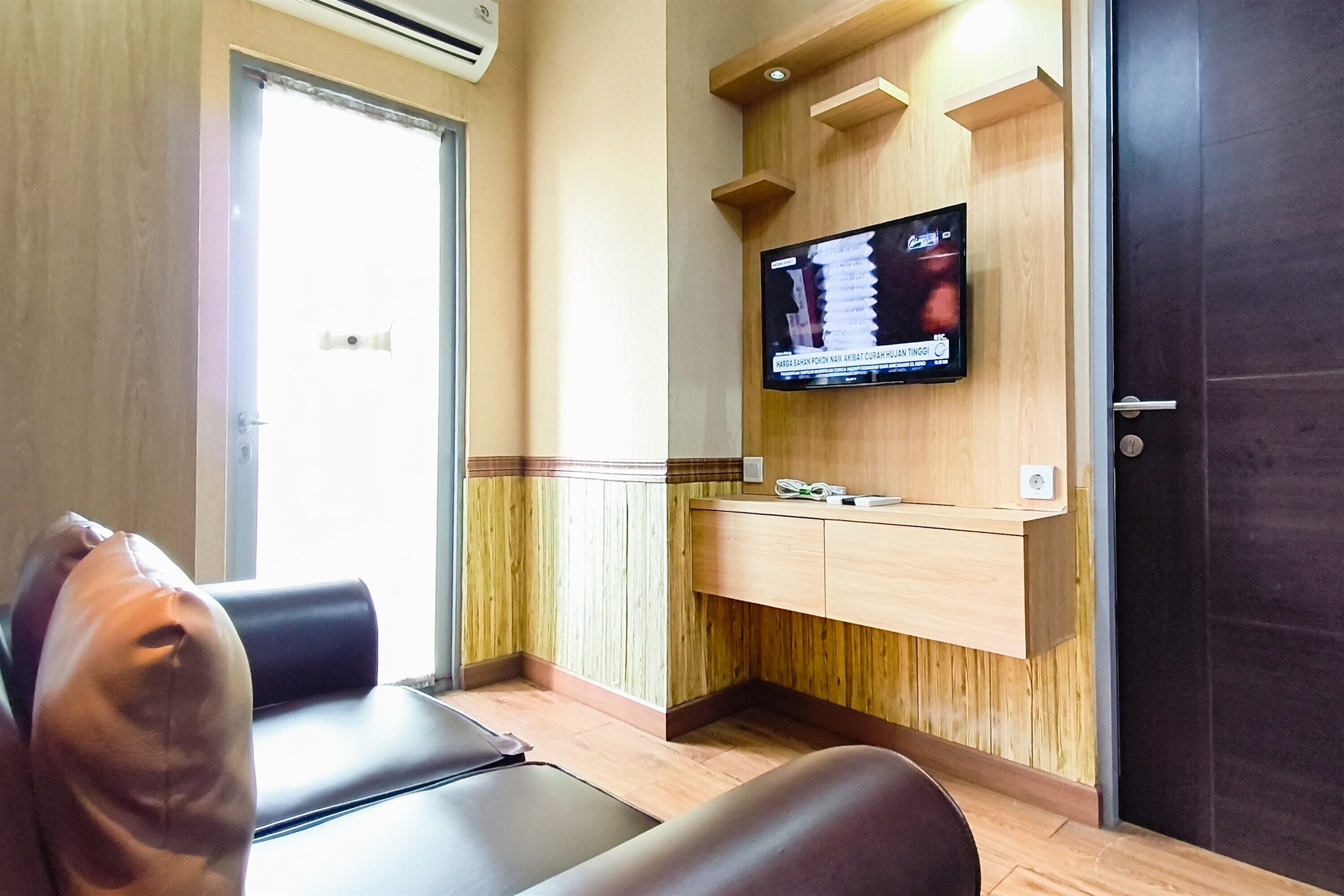 Una habitación con sillón de masajes, un mostrador de recepción de madera y un televisor montado en la pared.