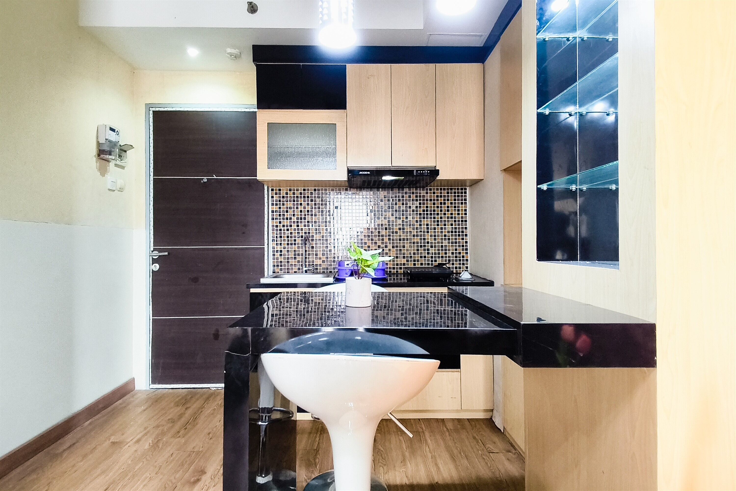 Una cocina compacta con encimera negra, un lavamanos blanco y salpicadero de azulejos.