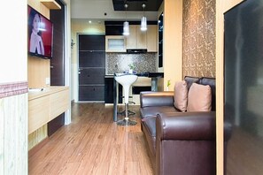 Un espace de vie moderne avec un canapé en cuir, une petite table et un téléviseur fixé au mur.