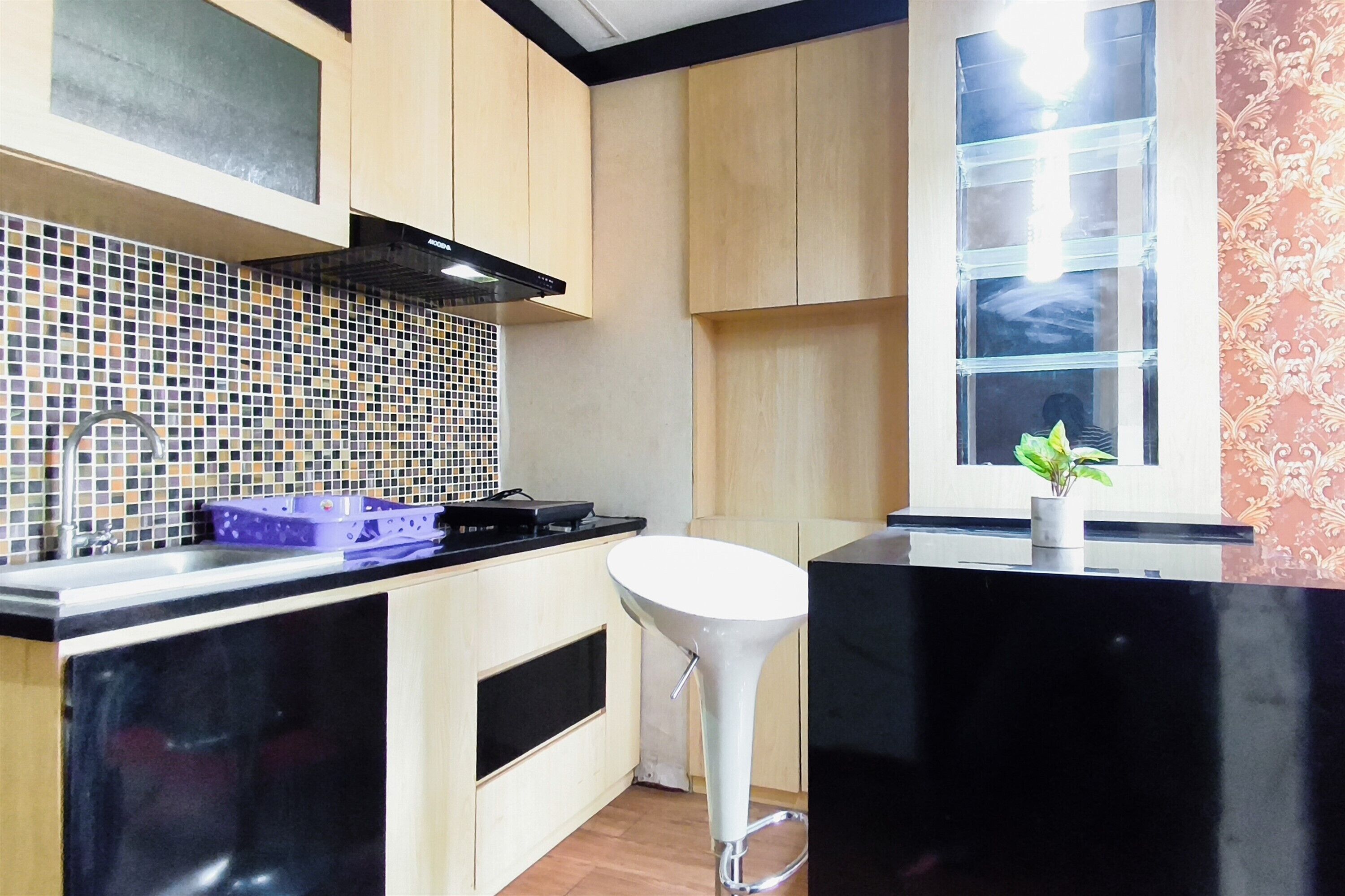 Una cocina con encimera negra, pileta blanca y salpicadero de azulejos.