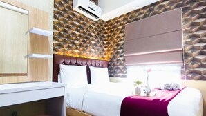 A bedroom with a bed, a desk, a chair, and a window with blinds. - Serene And Warm 1Br At Apartment Tamansari Prospero Sidoarjo (Sidoarjo)