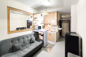 Ein gemütlicher Wohnbereich mit Sofa, Küchenzeile und Spiegel.
