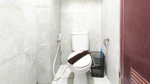 A small, tiled bathroom with a toilet, a hand dryer, and a trash bin. - Comfortable 2Br At Apartment Gateway Ahmad Yani Cicadas (Bandung)