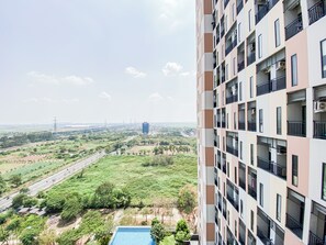 Un immeuble de grande hauteur doté de nombreux balcons et offrant une vue sur un paysage verdoyant, avec des arbres et une route.