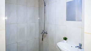 A bathroom with a shower, a sink, and a small potted plant. - Comfortable And Minimalist Studio Room At Apartment Grand Kamala Lagoon (Bekasi)