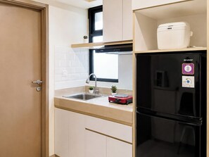 Eine kleine Küche mit Spüle, Herd und einem schwarzen Kühlschrank.