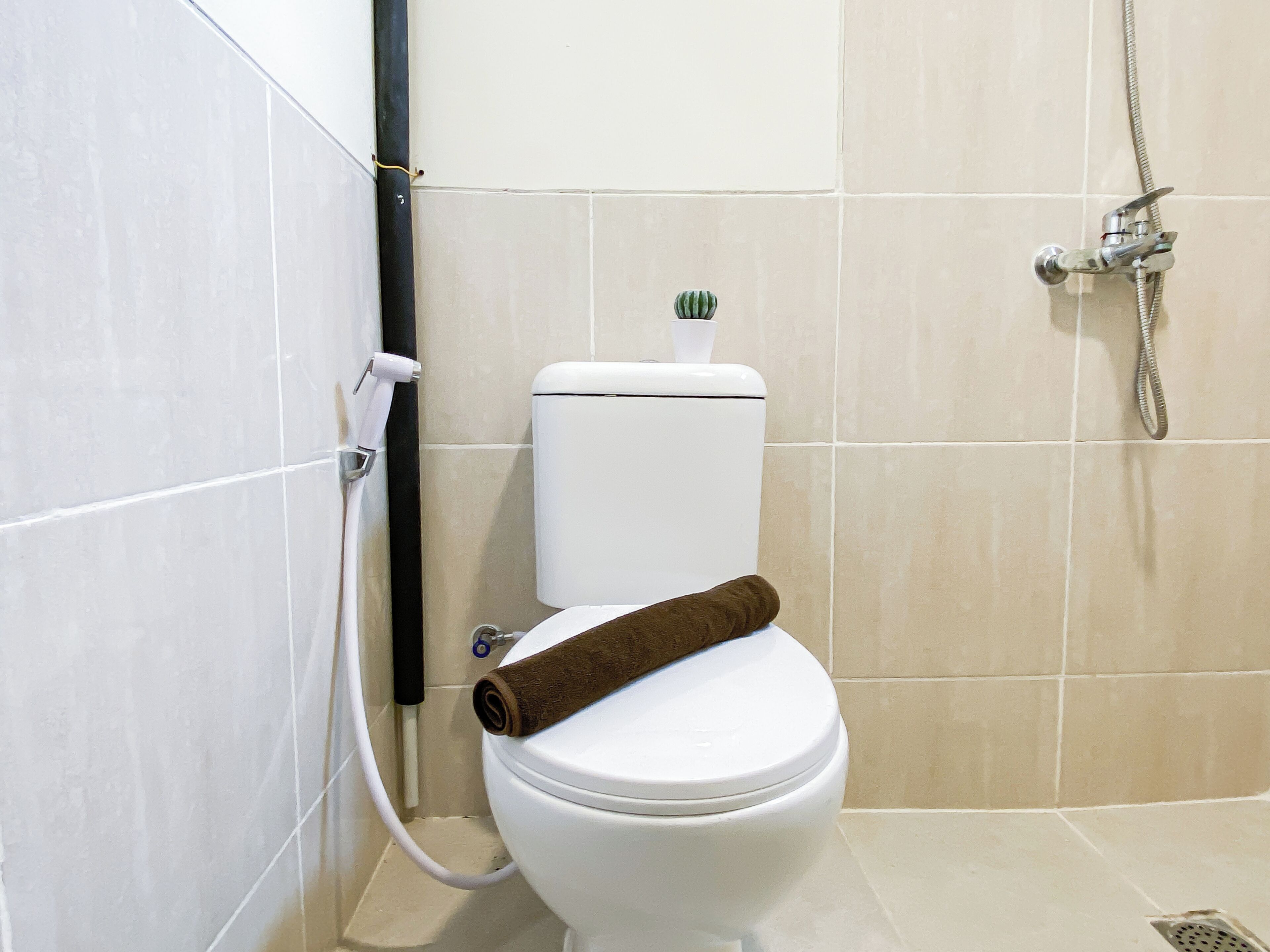 Un baño con inodoro, ducha y una toalla sobre el inodoro.