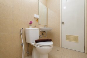 Un baño con inodoro, lavamanos y espejo.