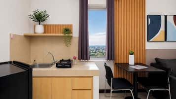 A compact kitchen with a built-in stove, a sink, and a window with curtains.