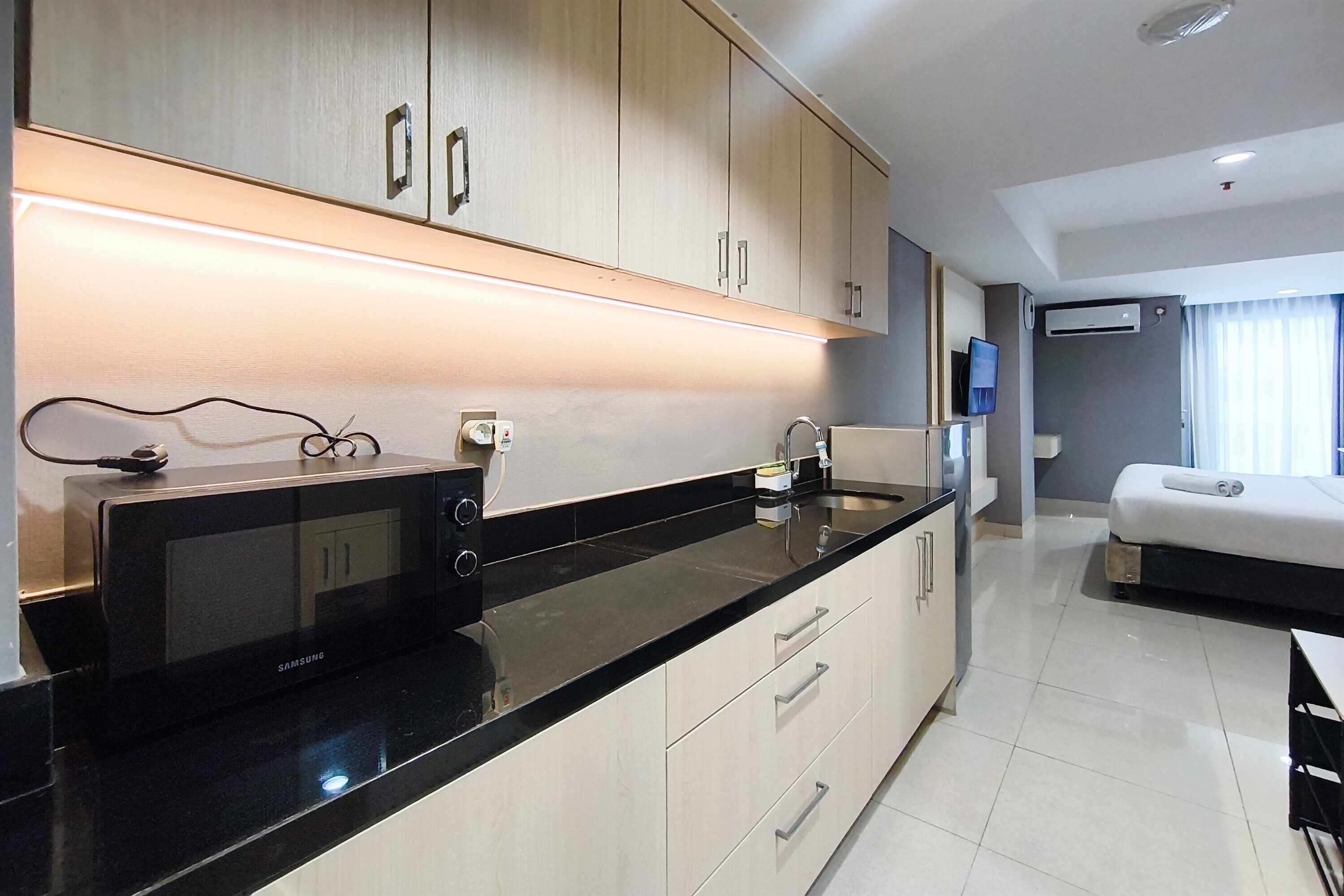 A modern kitchen with a black countertop, stainless steel appliances, and light-colored cabinetry.