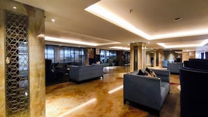 Um amplo hall com áreas de estar e uma mesa de recepção.