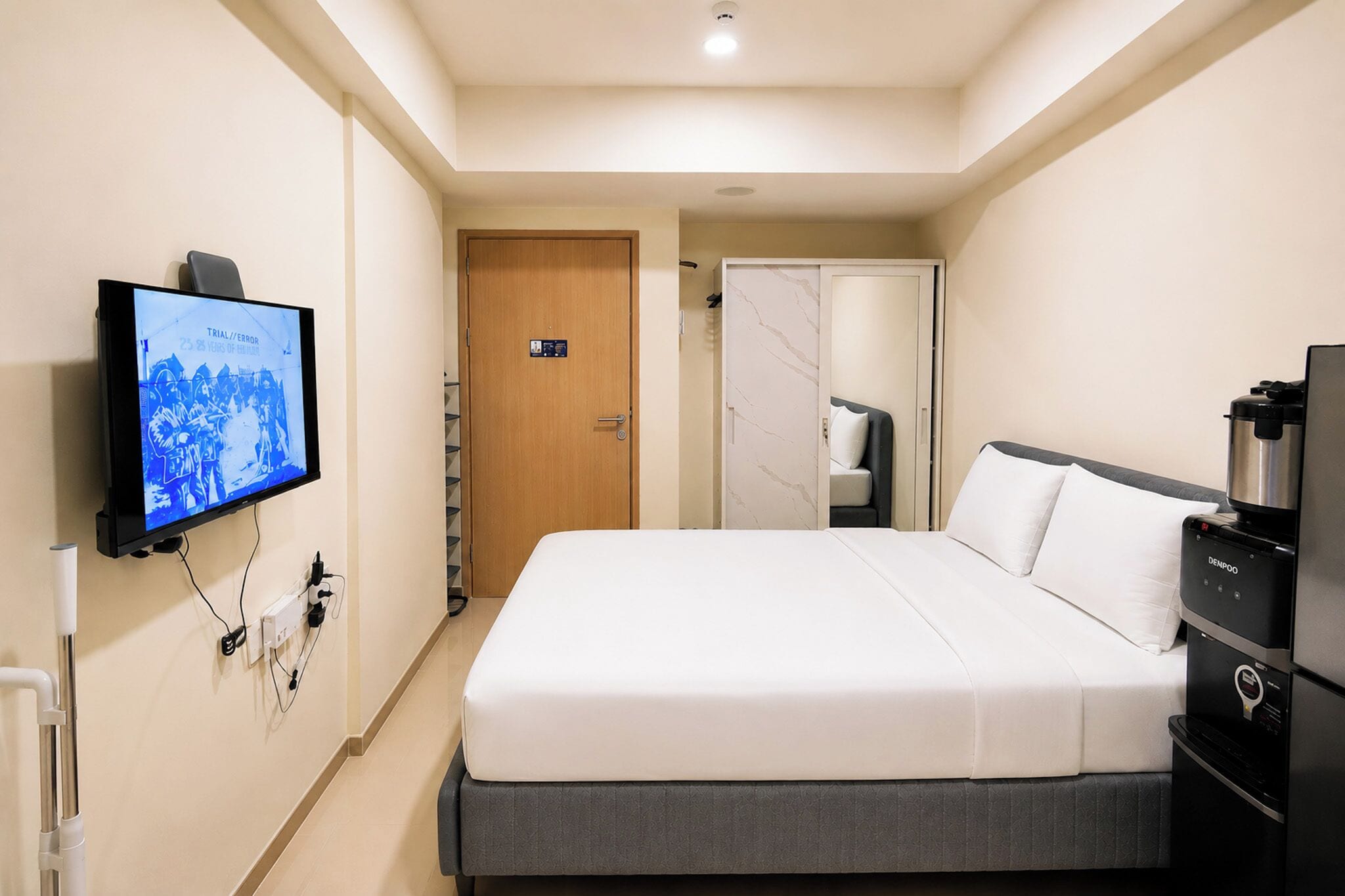 Una habitación de hotel con una cama, un televisor, una cafetera y un armario.