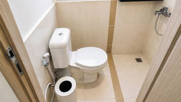 Un baño pequeño con inodoro, bidé y un ventanal.