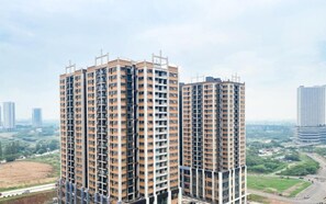 A high-rise residential building with multiple floors, large windows, and a modern architectural design. - Bright And Homey Studio Room At Apartment Meikarta District 1 (Cikarang)