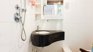 Ein Badezimmer mit einem schwarzen Waschbecken, einer Toilette und einer Dusche.