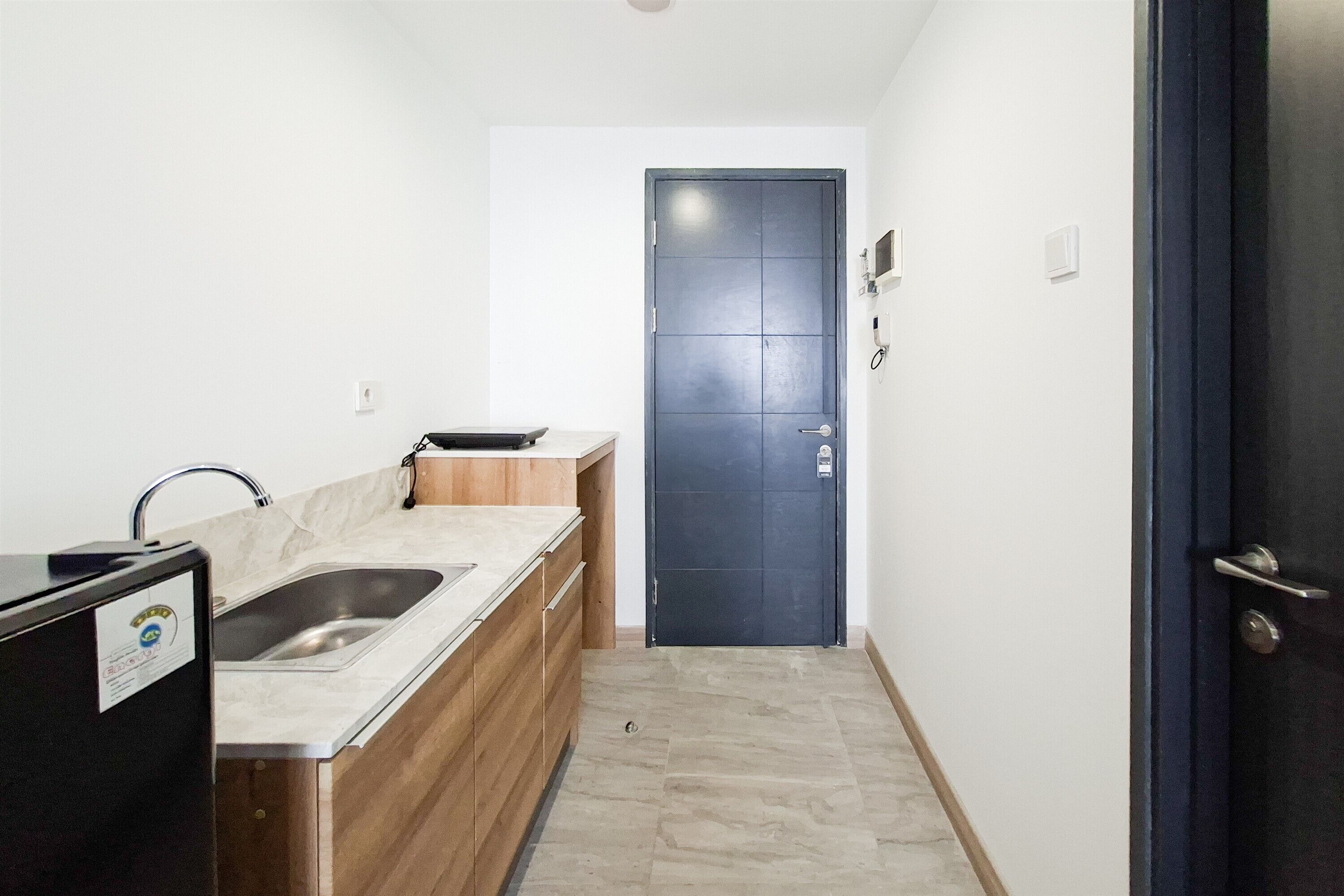 A small kitchenette with a double sink, a wooden countertop, and a black refrigerator.