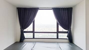 A room with a single window, a mattress, and curtains.