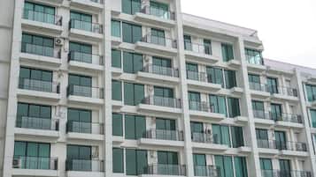 A multi-story building with balconies, large windows, and air conditioning units.