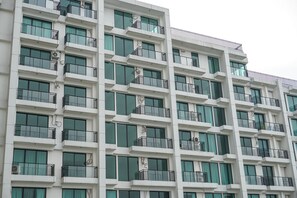 Un edificio de varios pisos con balcones, ventanas grandes y unidades de aire acondicionado.