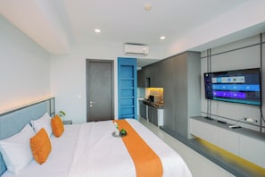 Una habitación de hotel moderna con una cama, un televisor montado en la pared y una zona de kitchenette.