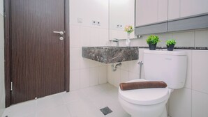 A bathroom with a toilet, sink, and a mirror. - Affordable Value Studio At Apartment Nine Residence (Jakarta)